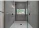 Walk-in shower with dual shower heads, gray tile walls and pebble tile flooring, framed by glass doors at 4021 Ohio Ave, Tampa, FL 33616