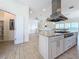 Kitchen with stainless steel hood vent, island cooktop, marble countertop and tile floors at 404 Hillsborough St, Palm Harbor, FL 34683