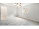 Spacious bedroom with neutral carpet, white walls, ceiling fan, window, and doorway to the bathroom at 4120 Marine Pkwy, New Port Richey, FL 34652