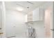 Bright laundry room features a utility sink, overhead storage cabinets and white painted door to hall at 4120 Marine Pkwy, New Port Richey, FL 34652