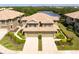 An aerial view of an elegant townhome with a tile roof surrounded by verdant landscaping and a tranquil pond at 7657 Caponata Blvd, Seminole, FL 33777