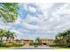 Welcoming gated community entrance with lush tropical landscaping and beautiful residential buildings at 7657 Caponata Blvd, Seminole, FL 33777