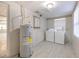 Bright laundry room featuring a washing machine, dryer, and water heater with gray tile flooring at 905 W Ball St, Plant City, FL 33563