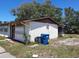 Exterior of the home with view of the side yard, showing a trash can and screened patio at 9355 Pinero St, Spring Hill, FL 34608