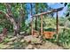 Backyard featuring a wooden swing set surrounded by trees and lush greenery at 9724 Hermit Hollow Ln, Gibsonton, FL 33534