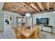 A dining area with exposed ceiling beams adjacent to an open bar and kitchen, with natural light at 9724 Hermit Hollow Ln, Gibsonton, FL 33534