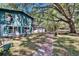 View of the home with green siding, surrounded by a large tree providing shade and a walkway to the garage at 9724 Hermit Hollow Ln, Gibsonton, FL 33534