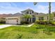 Charming two-story home featuring manicured lawn, lush landscaping, and a welcoming front entrance with a three car garage at 10142 Deercliff Dr, Tampa, FL 33647