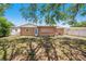 View of the backyard and rear facade of the house with a grass yard, tree, and partial fence at 1051 Normandy Blvd, Holiday, FL 34691