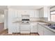 Traditional kitchen with white cabinetry, matching appliances, and laminate countertops at 1051 Normandy Blvd, Holiday, FL 34691