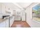 Efficient kitchen with white appliances, wood floors, and a bright window view at 1051 Normandy Blvd, Holiday, FL 34691