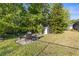 Landscaped backyard with a quaint outdoor dining area and a charming storage shed surrounded by mature trees at 10726 Miracle Ln, New Port Richey, FL 34654