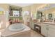 Large bathroom with garden tub, double sinks, makeup vanity, and arched windows allowing natural light at 10726 Miracle Ln, New Port Richey, FL 34654