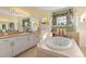 Bathroom with a large garden tub, double sinks, vanity area, and arched windows at 10726 Miracle Ln, New Port Richey, FL 34654