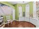 Cozy green bedroom with dual windows, built-in storage, and a decorative mandala wall hanging above a chair at 10726 Miracle Ln, New Port Richey, FL 34654