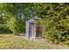Charming outdoor storage shed nestled amidst lush greenery and mature trees in the backyard at 10726 Miracle Ln, New Port Richey, FL 34654