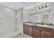 Well-lit bathroom features a walk-in shower, double vanity with granite countertops at 10936 Rainbow Pyrite Dr, Wimauma, FL 33598