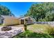 Spacious backyard featuring brick patio, a fire pit, green lawn, mature trees and the exterior of the home at 1120 Country Ln, Lutz, FL 33558