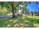 Large, well-maintained backyard featuring mature trees providing ample shade and a charming exterior at 1120 Country Ln, Lutz, FL 33558