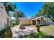 Outdoor patio area with brick flooring, a fire pit, tall trees and the exterior of the home at 1120 Country Ln, Lutz, FL 33558