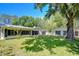 Charming home exterior with large windows, lush lawn, mature trees, and a separate structure at 1120 Country Ln, Lutz, FL 33558