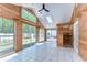 Vaulted sunroom with wood-paneled walls, white tile flooring, and a backyard view at 1120 Country Ln, Lutz, FL 33558
