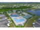 Aerial view featuring a community pool, tennis court, playground, and clubhouse next to a scenic pond at 12123 Ledbury Commons Dr, Gibsonton, FL 33534
