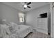 This bedroom offers a ceiling fan, wood look flooring, a small window with white curtains, and a television on top of a cabinet at 12123 Ledbury Commons Dr, Gibsonton, FL 33534