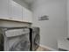 Well-equipped laundry room with modern washer and dryer, complemented by overhead cabinets and a laundry sign at 12123 Ledbury Commons Dr, Gibsonton, FL 33534