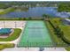 Aerial view of a well-maintained community tennis court with basketball court and a pond in the background at 12123 Ledbury Commons Dr, Gibsonton, FL 33534