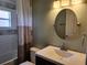 Bathroom featuring a modern vanity, round mirror, tub/shower, and warm lighting to create a spa-like ambiance at 13400 Old Florida Cir, Hudson, FL 34669