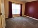 A carpeted bedroom with a window providing natural light and dark red curtains at 13400 Old Florida Cir, Hudson, FL 34669