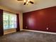 Bright bedroom with natural light, plush carpeting, and a striking dark red accent wall at 13400 Old Florida Cir, Hudson, FL 34669