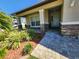 Charming home entrance featuring a stone accented porch, decorative plants, and tiled walkway at 13400 Old Florida Cir, Hudson, FL 34669