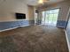 Spacious living room with plush carpet, large windows, and access to the outdoor pool area at 13400 Old Florida Cir, Hudson, FL 34669