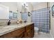 Bathroom featuring double sinks with granite countertops, wood cabinets, and a blue patterned shower curtain at 1603 S Arrawana Ave, Tampa, FL 33629