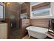 Bathroom featuring a glass shower, a clawfoot tub, and a large window for natural light at 1603 S Arrawana Ave, Tampa, FL 33629