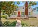 Charming home showcasing a well-manicured lawn, red brick chimney and quaint, orange front door with green shutters at 1603 S Arrawana Ave, Tampa, FL 33629