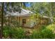 Home exterior showing the wraparound porch, mature landscaping, and unique architectural style at 187 Sage Cir, Crystal Beach, FL 34681