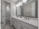Bathroom features double vanity with white countertops, a large mirror, modern fixtures and tiled floors at 19554 Roseate Dr, Lutz, FL 33558