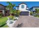 Two-story home boasts a brick-paved driveway, a two-car garage, and lush tropical landscaping at 19554 Roseate Dr, Lutz, FL 33558