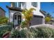 Charming home features a gray garage door, black framed windows, and tropical landscaping at 19554 Roseate Dr, Lutz, FL 33558