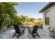 Charming backyard featuring a stone patio with Adirondack chairs, palm trees, and tropical landscaping at 19554 Roseate Dr, Lutz, FL 33558