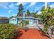 Charming, one-story home featuring a bright, turquoise exterior, manicured landscaping, and a unique chimney design at 2016 Douglas Ave, Clearwater, FL 33755