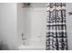 Shower-tub combination featuring white tiled surround and modern shower curtain at 25324 Lexington Oaks Blvd, Wesley Chapel, FL 33544