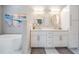 Bright bathroom with double vanity, tub, beach-themed artwork, and white cabinets and countertops at 25324 Lexington Oaks Blvd, Wesley Chapel, FL 33544