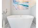 A freestanding soaking tub with floor mounted filler in a Primary bathroom with beach themed artwork at 25324 Lexington Oaks Blvd, Wesley Chapel, FL 33544