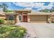 Inviting single-story home featuring a brick walkway, manicured lawn, and an eye-catching red front door at 25324 Lexington Oaks Blvd, Wesley Chapel, FL 33544