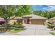 Charming single-story home with a well-manicured lawn, mature trees, and a welcoming red front door at 25324 Lexington Oaks Blvd, Wesley Chapel, FL 33544