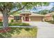 Charming single-story home featuring a well-manicured lawn, mature tree, and inviting red front door at 25324 Lexington Oaks Blvd, Wesley Chapel, FL 33544